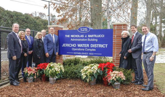 Group photo at sign dedication, Nicholas J. Bartilucci Administration Building, Jericho Water District. Left to right Jericho Water District Commissioner James Asmus; Oyster Bay Town Council member Vicki Walsh; Oyster Bay Town Clerk Richard LaMarca; Jericho Water District Commissioner Patricia Beckerle; Jericho Water District Board Chairman Commissioner Thomas Abbate; Town of Oyster Bay Supervisor Joseph Saladino; Mrs. Joan Bartilucci; Jericho Water District Superintendent Peter Logan; Nassau County Legislator Josh LaFazan (18th Legislative District).